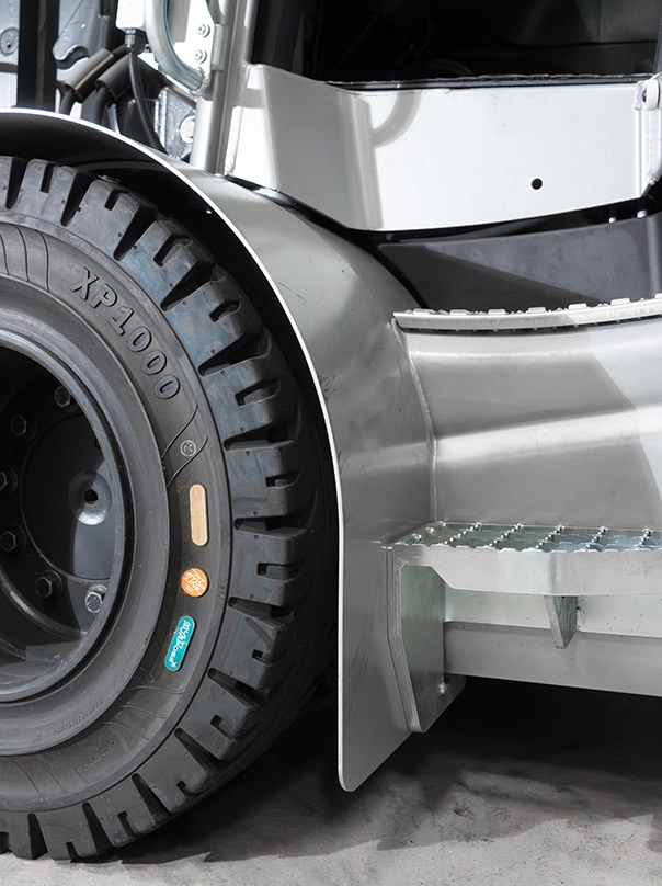 Close-up of an industrial truck’s front wheel, with an XP1000 tyre, a metal fender and a galvanised entry step.