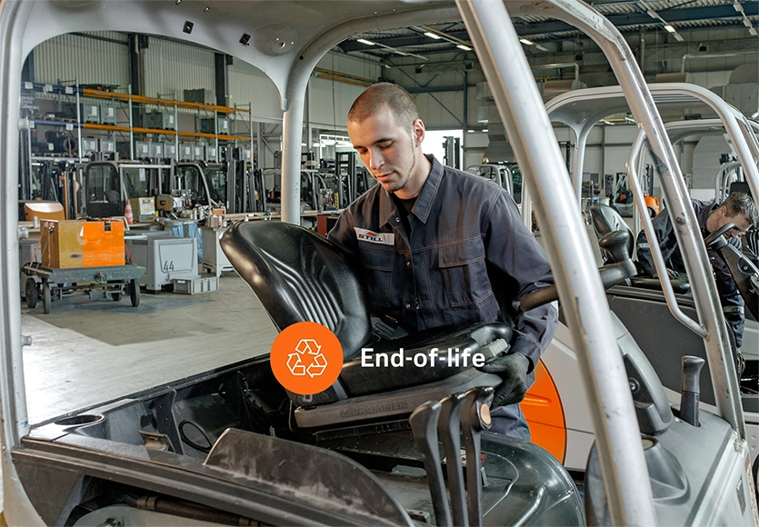 A STILL employee removes the driver’s seat from a used forklift in a workshop, labelled “End-of-life”.