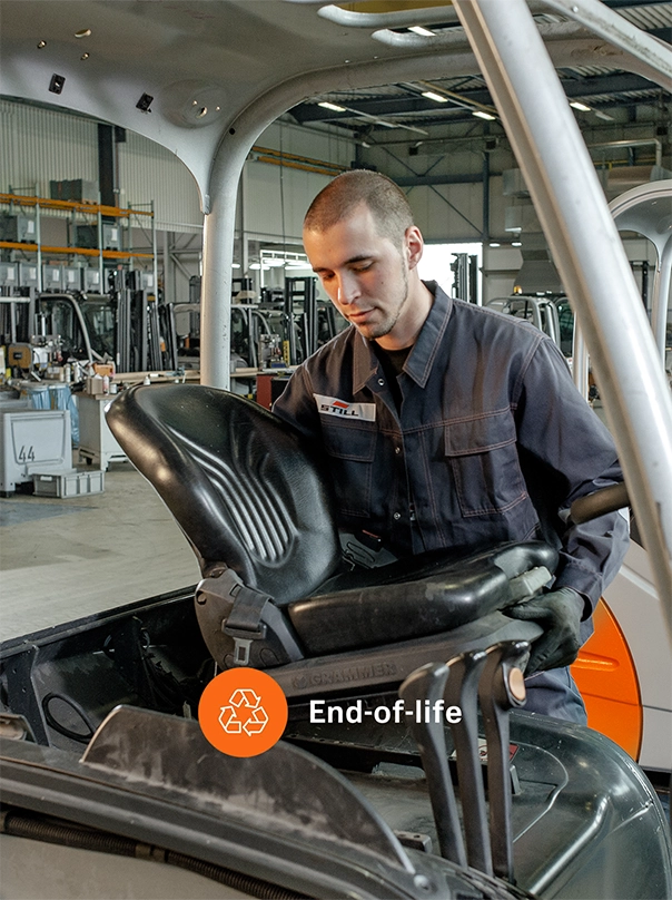 A STILL employee removes the driver’s seat from a used forklift in a workshop, labelled “End-of-life”.